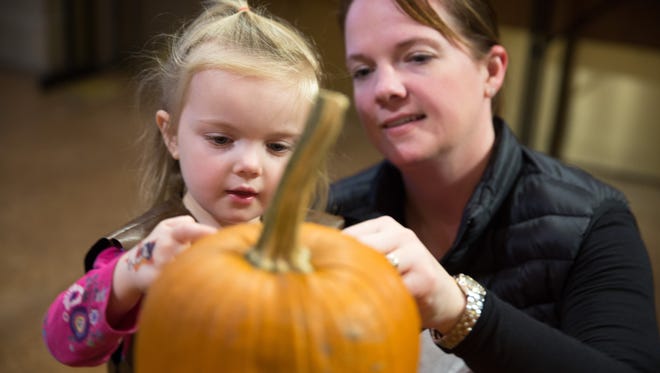 Ellie Teas, 3, and Amy Teas of West Des Moines, decorate a pumpkin Friday, Oct. 23, 2015, during Halloween Hoopla at Raccoon River Park in West Des Moines.