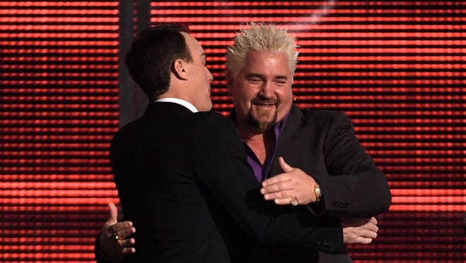 Chef and television personality Guy Fieri, right, hugs Kevin Harvick during the 2016 NASCAR Sprint Cup Series Awards.