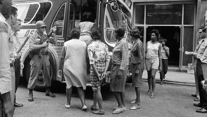 Women prisoners arrested for various offenses during the rioting in Detroit, July 28, 1967, board a bus at Wayne County Jail under the eyes of National Guardsmen.