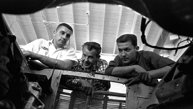 Lee Petty, center, and his sons Maurice, left, and Richard look into the empty engine well of a new race car in their garage in Level Cross, N.C. in 1964.