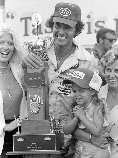 Richard Petty, with daughter Becky and wife Lynda, right, at his side, holds his trophy in the victory lane after he won the Firecracker 400 in 1977.