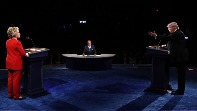 Republican presidential nominee Donald Trump speaks as Democratic presidential nominee Hillary Clinton and Moderator Lester Holt listen during the presidential debate at Hofstra University.