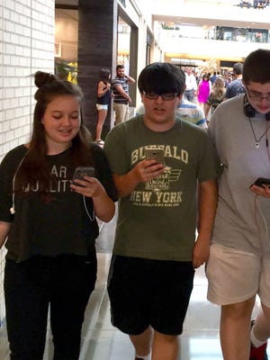 Mia Melugin, 13, her brother Liam Melugin, 16, and their friend Joshua Loughren, 16, play Pokemon Go while walking around the NorthGate Center mall in Dallas.