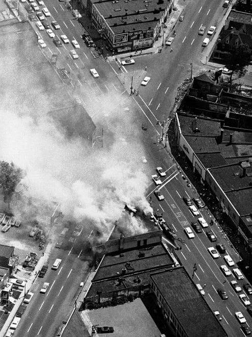 In this July 25, 1967 photo, smoke rises from a fire set at the busy intersection of Grand River and 14 Street in Detroit, near another burned out building. The fire was set despite patrols by the National Guard, police and Army troops.