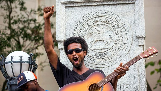 Isaiah Wallace plays his guitar standing on the base that formerly supported a Confederate soldier statue after a group of protesters pulled it down during a rally Monday, Aug. 14, 2017, in Durham, N.C. Protesters toppled the nearly century-old statue of a Confederate soldier Monday at the rally against racism. The Durham protest was in response to a white nationalist rally held in Charlottesville, Va., over the weekend. (Casey Toth/The Herald-Sun via AP)