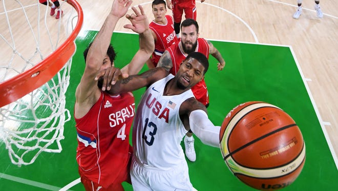 United States basketball guard Paul George goes up for a shot while guarded by Serbia point guard Milos Teodosic.