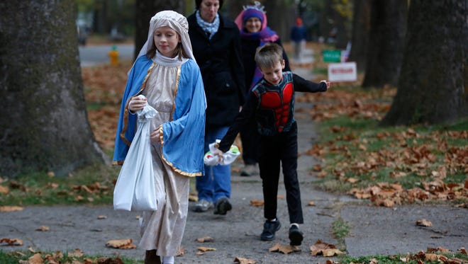 Emma, 10, and Leo Gannon, 7, lead their mother Debbie Gannon and grandmother Susan King down the sidewalk Friday, Oct. 30, 2015, as they start out their trek for candy on Beggars' Night in Des Moines.