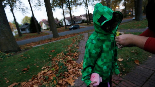 Shaye Mapes, 6, gets zipped into her Minecraft costume Friday, Oct. 30, 2015, before heading out on Beggars' Night in Des Moines.