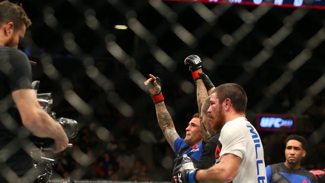 Dustin Poirier (red gloves) raises his arms in victory after defeating Jim Miller (blue gloves) during UFC 208 at Barclays Center.