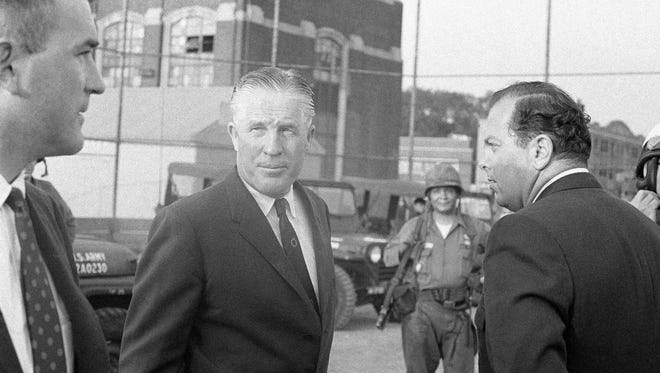 Gov. George Romney, center, confers with Mayor Jerome Cavanagh, right, of Detroit as National Guardsmen standby in a part of Detroit that was ravaged by rioters, July 24, 1967. Romney called in the guardsmen as rioters firebombed and pillaged a wide area of the city.