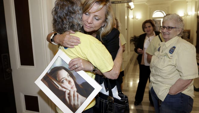 In this Sept. 9, 2015, file photo, Debbie Ziegler holds a photo of her late daughter, Brittany Maynard, as she receives congratulations from Ellen Pontac, left, after a right-to die measure was approved by the state Assembly in Sacramento, Calif.
