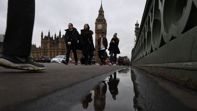 Commuters walks over Westminster bridge by the Houses of Parliament in central London on March 29, 2017.