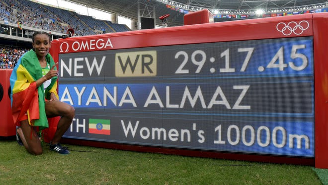 Almaz Ayana of Ethiopia poses with the scoreboard after setting a world record while winning gold in the women's 10,000 at Estadio Olimpico Joao Havelange in the Rio 2016 Summer Olympic Games.