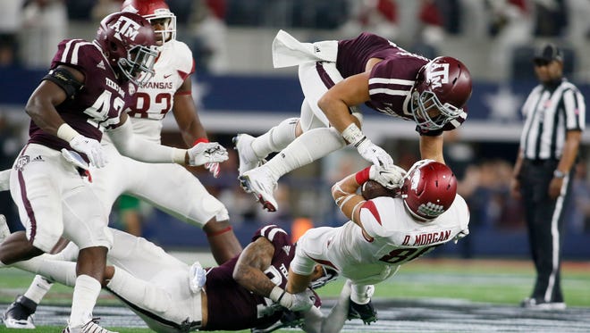 Arkansas Razorbacks wide receiver Drew Morgan (80) is tackled by Texas A&M Aggies linebacker Richard Moore (7) and defensive back Priest Willis (24) in the second quarter at AT&T Stadium.
