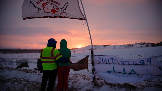 Charlotte Saxton, right, and her father Robert, left, both from Bemidji, MN, enjoy a sunset in the Oceti Sakowin Camp on Monday, Dec. 5, 2016 near Cannon Ball.