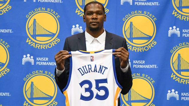 Kevin Durant poses for a photo with his jersey during a press conference after signing with the Golden State Warriors.