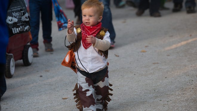 William Vasey, 1, of Indianola, struts his stuff as a cowboy while trick-or-treating during Night Eyes at Blank Park Zoo in Des Moines, Iowa, Thursday, Oct. 15, 2015.
