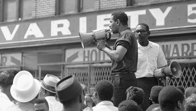 Congressman John Conyers, Detroit Democrat, uses a bullhorn as he tried to encourage African Americans in Detroit's riot area to go home, July 23, 1967. He was met with shouts of "No, no." As Conyers stepped down a rock hit the street a few feet from him.