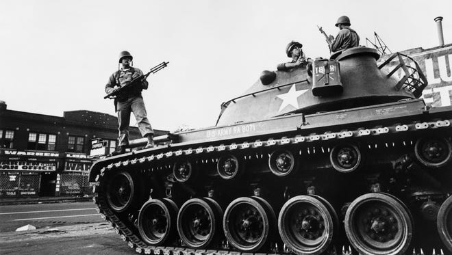 Federal soldiers stand guard on a tank in a Detroit street on July 25, 1967 during riots that erupted in Detroit.