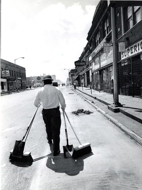 A man is seen cleaning up debris after the1967 Riots.
