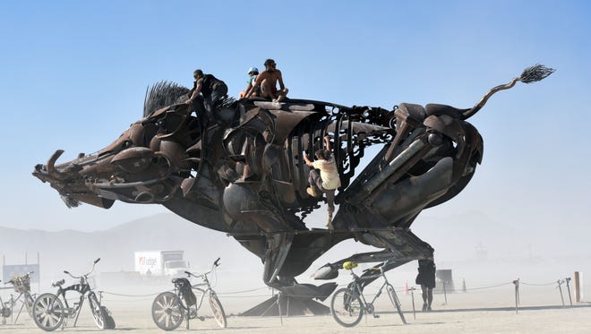 Burning Man attendees ride atop a rotating wild boar sculpture. One of Burning Man's core principles is presence, encouraging people to be present with those around them, instead of engaging with their iPhones or other technology.
