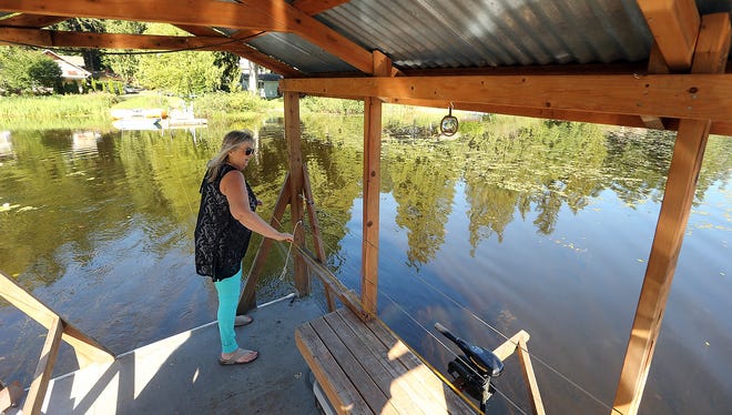 Teri Allen, a broker with Karen Kay Properties, uses a rope to pull the ferry across the water away from the shore of Island Lake and to the Clark Island property on Monday. The roughly 1-acre island, with a three-story main house and a smaller bunk house, is for sale.
