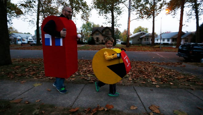 Rob Fox (left) and Calvin Waggoner, 6, walk from house to house in their Pac-Man costumes Friday, Oct. 30, 2015, during Beggars' Night in Des Moines. Fox said he and Waggoner have worn matching themed costumes for several years, with Waggoner picking the Pac-Man theme after watching the movie "Pixels."