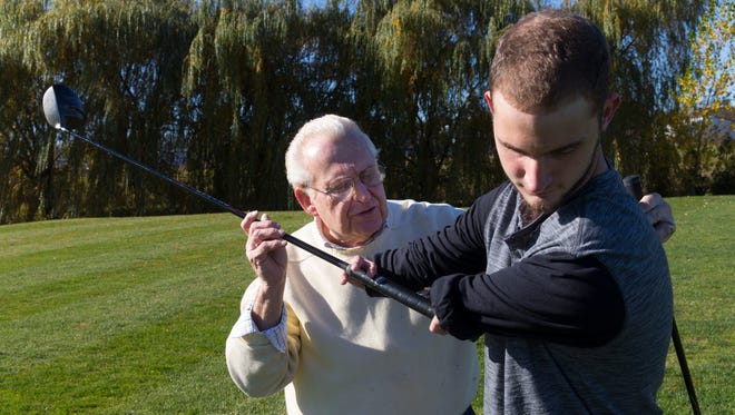 Ricky Kaufert, born with deformed arms that end at the elbows, gets help with his golf swing from Bob Burns.