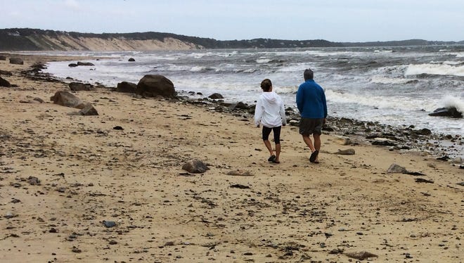 A couple walks along Sagamore Beach as Hermine whips up heavy surf on Cape Cod Bay on Sept. 5, 2016, in Bourne, Mass. Hermine continued Monday to twist hundreds of miles off shore in the Atlantic Ocean and was expected to keep swimmers and surfers out of beach waters because of its dangerous waves and rip currents on the last day of the long holiday weekend.