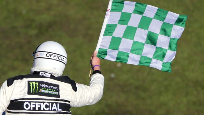 An official waves the green checkered flag to signal the end of the first race segment.