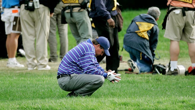 Phil Mickelson kneels down as the media watches Tiger Woods hit Mickelson's errant drive from along a fence on the 18th hole of their foursomes match at the 35th Ryder Cup at Oakland Hills Country Club in Bloomfield Township, Mich., in 2004. Mickelson and Woods lost   1-up.