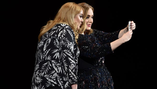 Adele poses with a fan for a selfie at Genting Arena on March 29, 2016, in Birmingham, England.