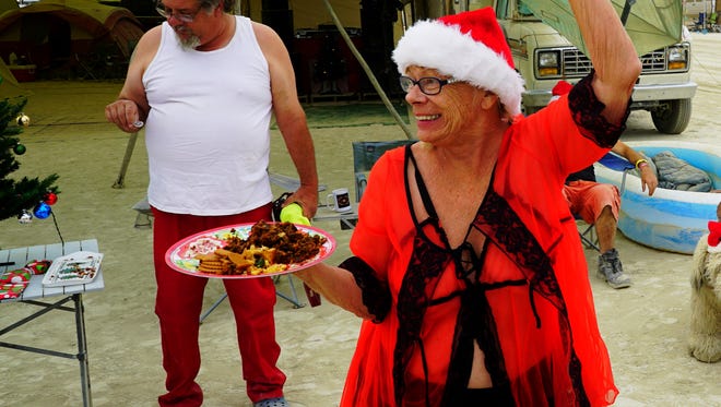 Sunshine Rudiak, dressed in lingerie and a Santa hat, waves to passers-by while offering free fruitcake and Christmas cookies at Burning Man in Black Rock Desert, Nev., on Sept. 3.