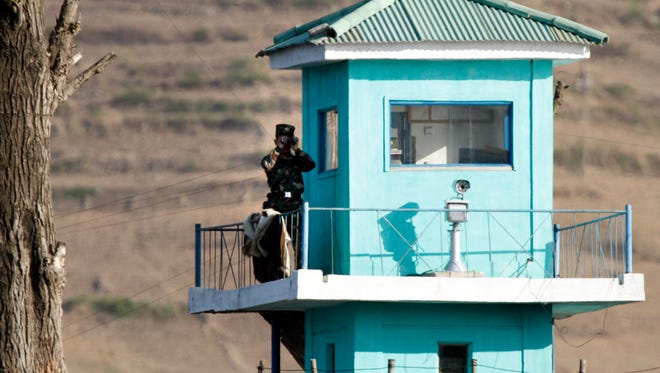 In this Wednesday, May 3, 2017 photo, a North Korean soldier looks through a pair of binoculars as he stands at a guard tower on the border near Chongsu in North Korea's North Pyongan Province, as seen from across the border in Dandong in northeastern China's Liaoning Province.