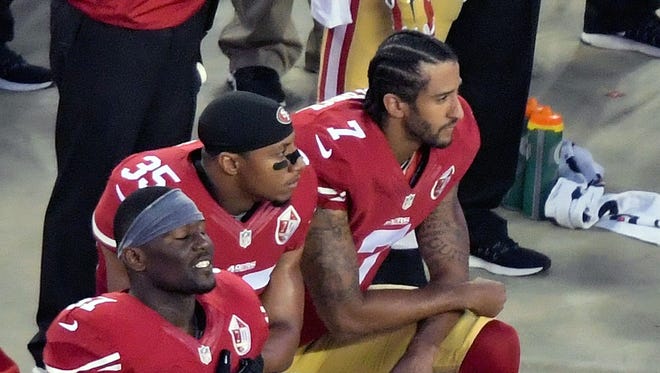 49ers teammates Colin Kaepernick (7) and Eric Reid (35) kneel during the anthem before the season opener.